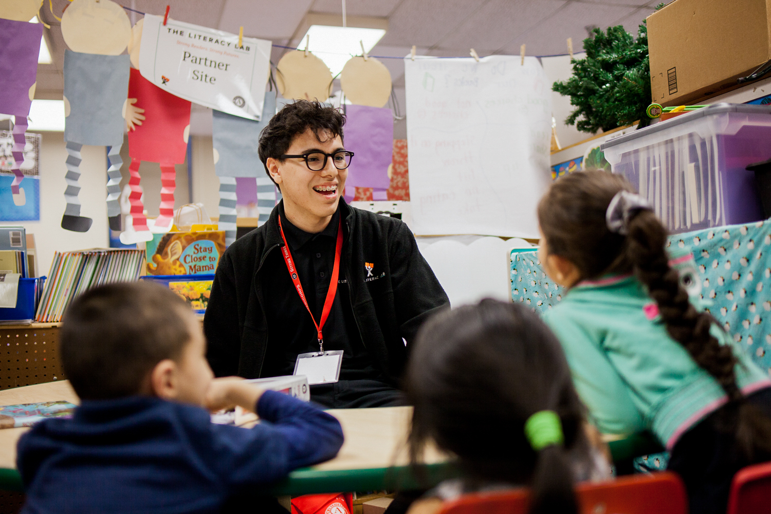 Tutor sitting at a desk with young children.