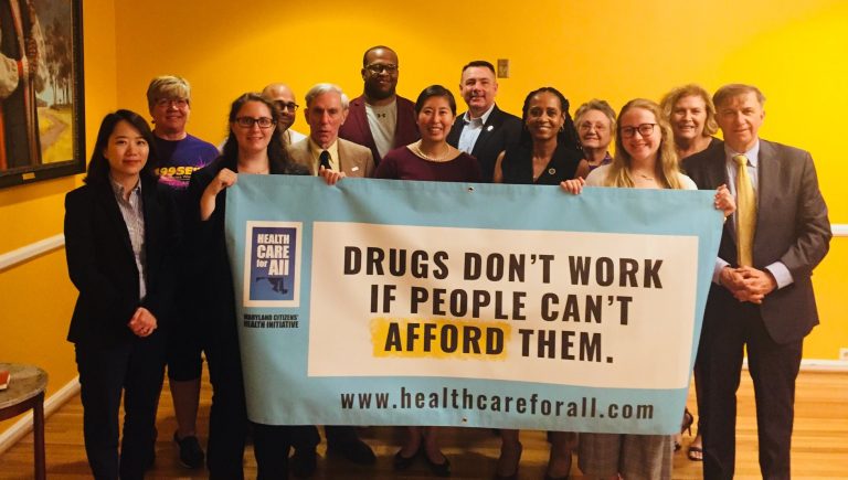 Group of people pose with a banner reading, "Drugs Don't Work if People Can't Afford Them"