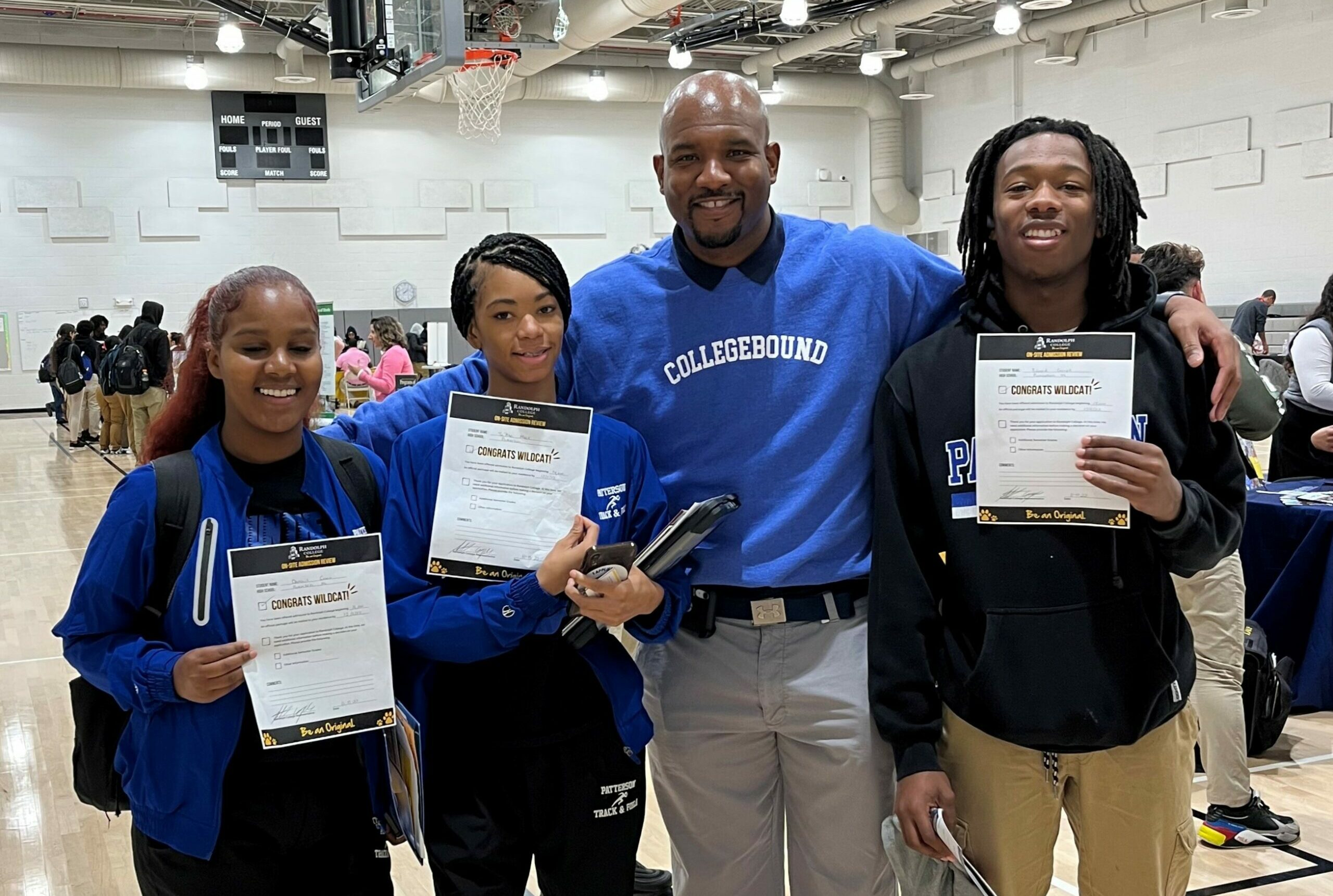Three students show off college acceptance letters alongside a teacher.