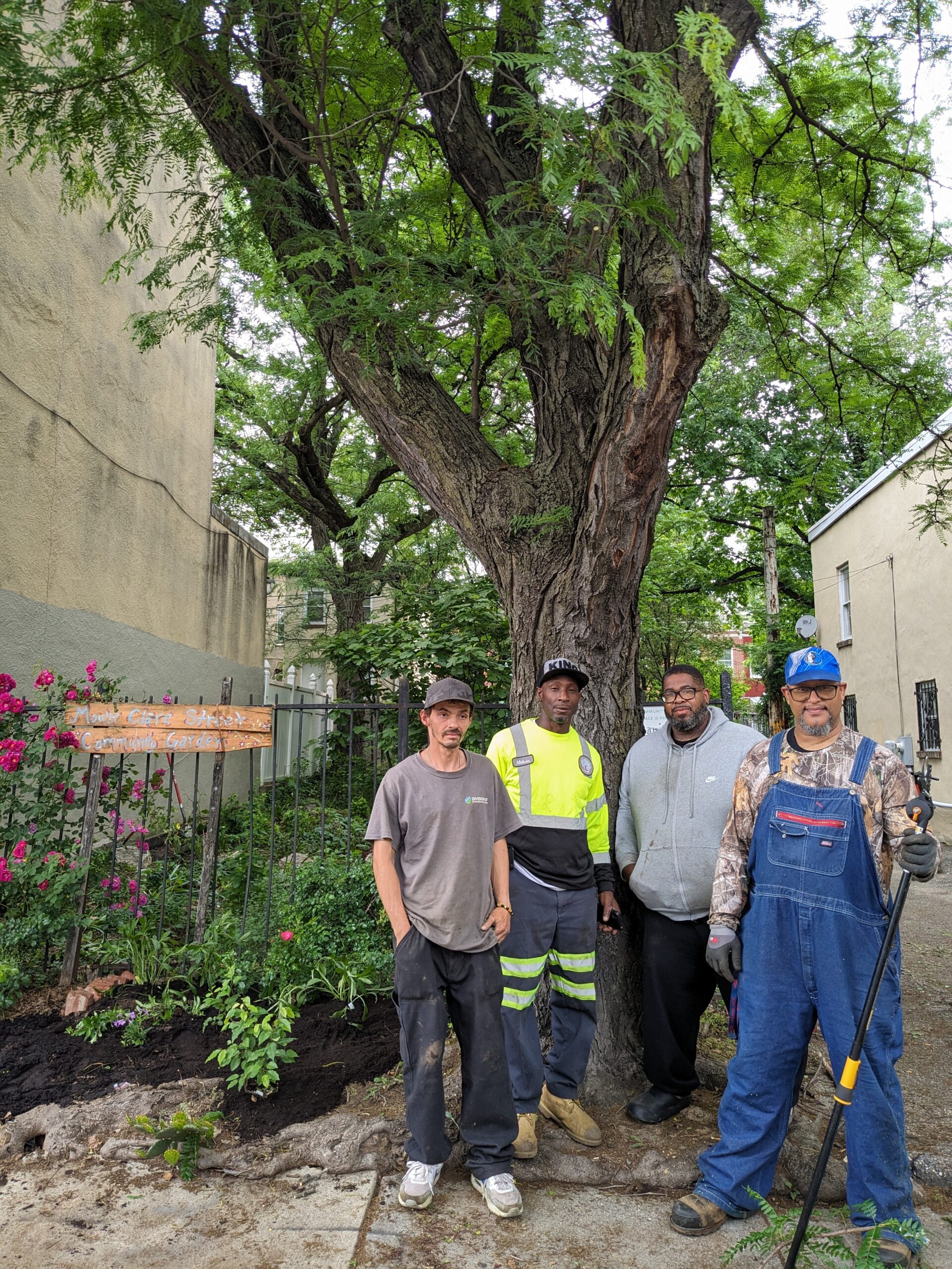 Four men pose for a picture in a community garden.