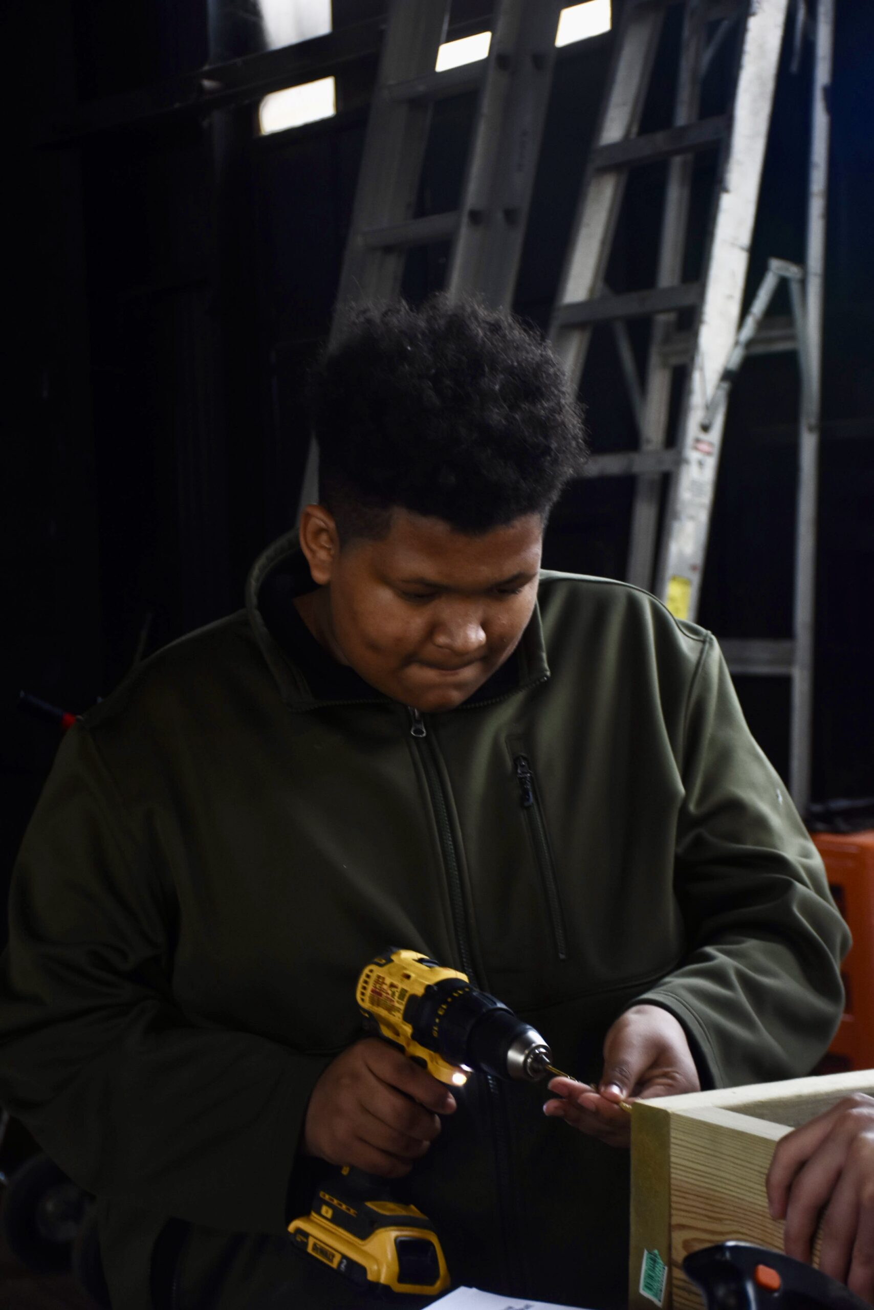 Young person uses a power drill.